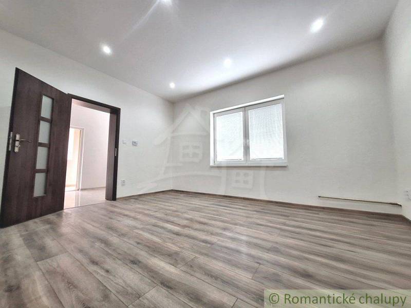 Rodinný dům s laminátovou podlahou, bílými stěnami a oknem s vnitřními žaluziemi.
