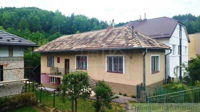 Rodinný dům ve Fričovcích se šikmou střechou, zahradou a okolním lesem.