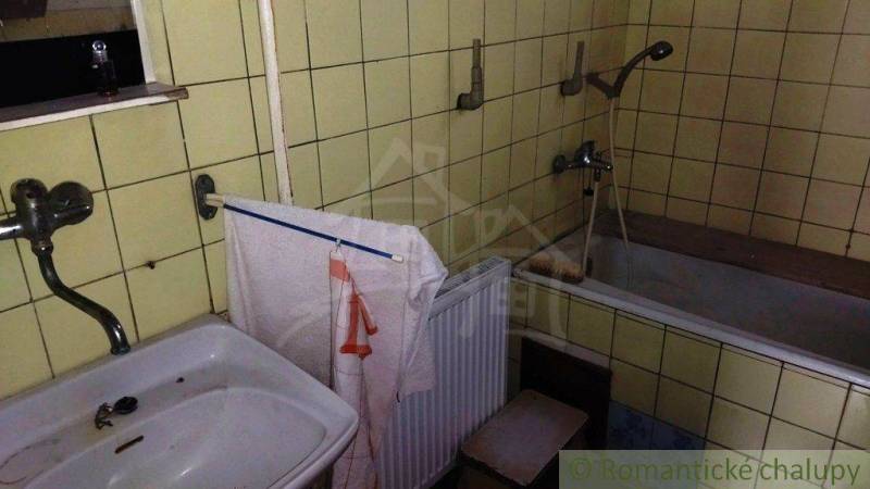 Koupelna v rodinném domě s umyvadlem, vanou a žlutými obklady.