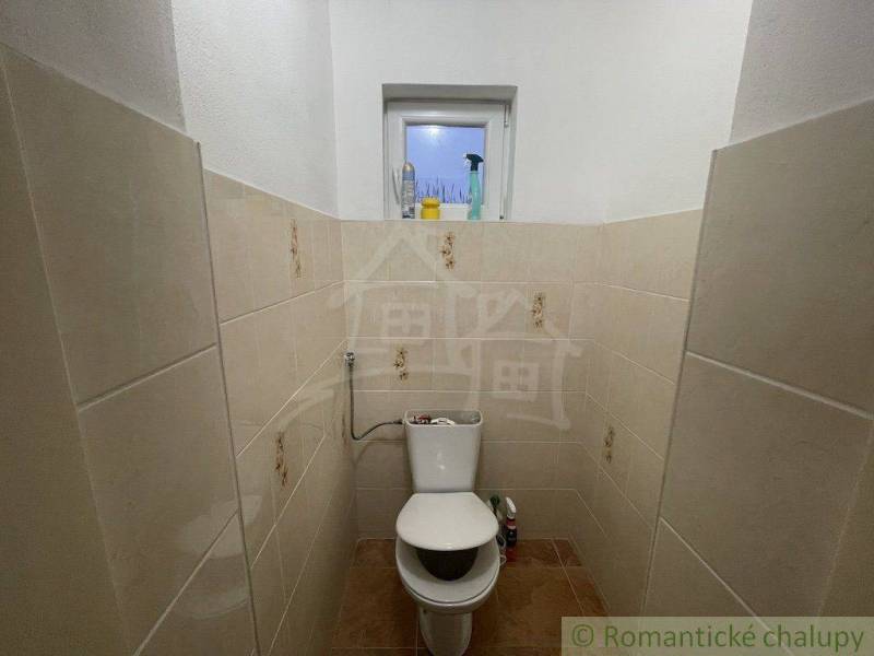 Malá koupelna s keramickými obklady, WC a oknem v rodinném domě.