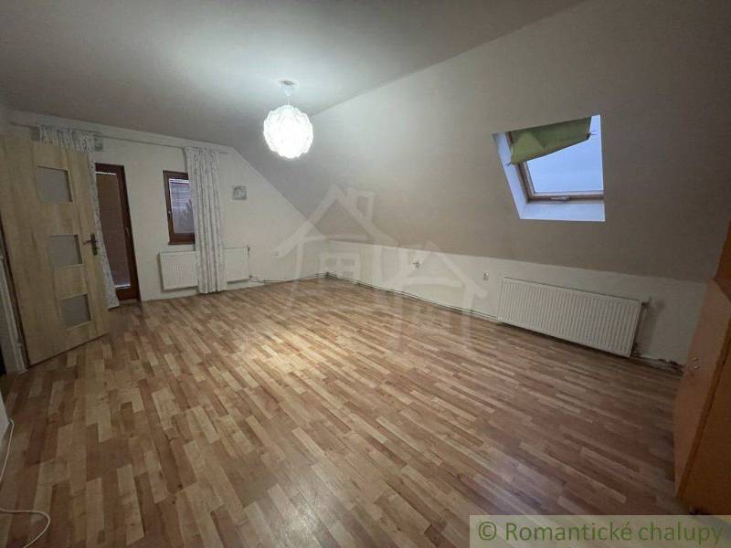 Podkrovní pokoj v rodinném domě s laminátovou podlahou a střešním oknem.