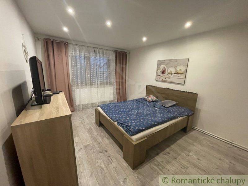 Ložnice s manželskou postelí, televizorem a obrazem, součást rodinného domu.