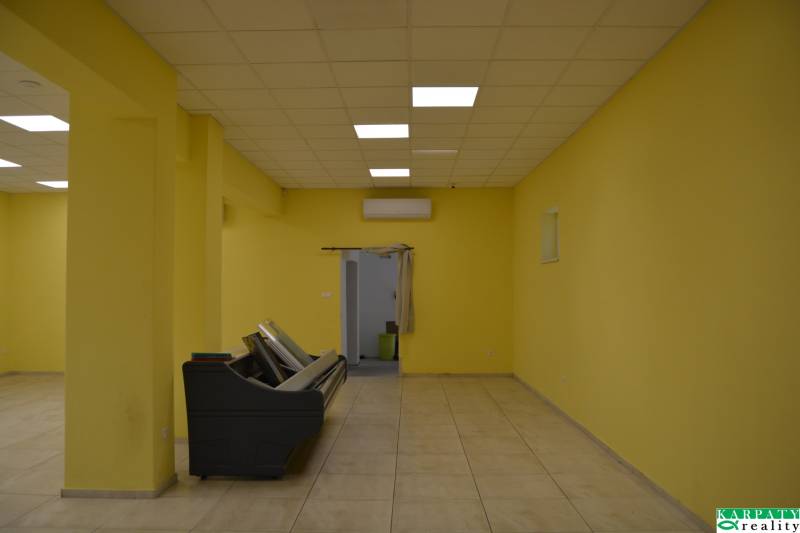 Žluté stěny, dlažba a stropní světla v obchodních prostorách.