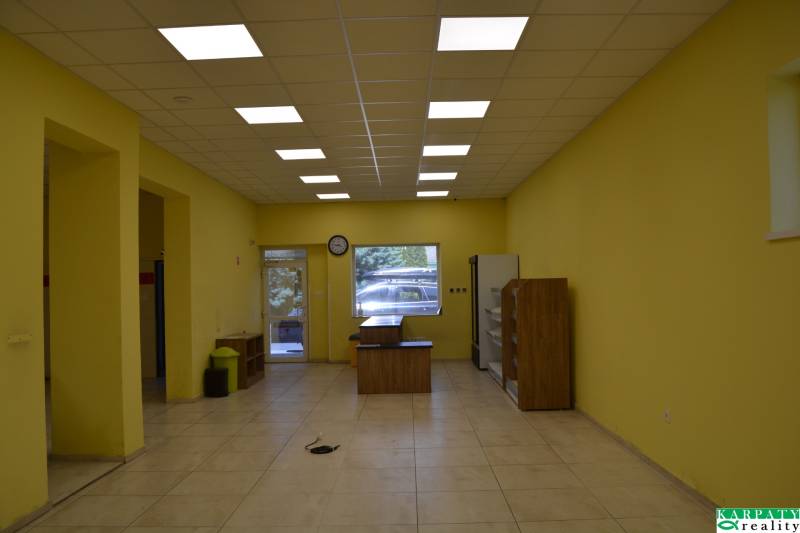 Žluté stěny, stropní osvětlení, nábytek a vstupní dveře v obchodních prostorách.