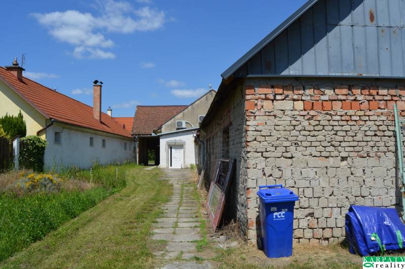 Obchodní prostory v Borském Svätém Juru, budovy s červenou střechou, trávník a modrý kontejner.