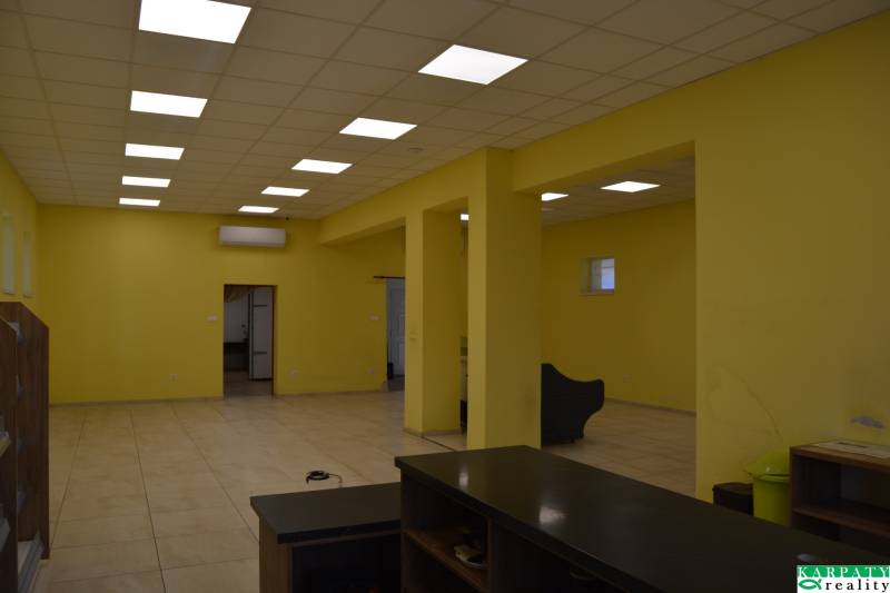 Interiér obchodních prostor s výraznou žlutou stěnou a stropními světly.