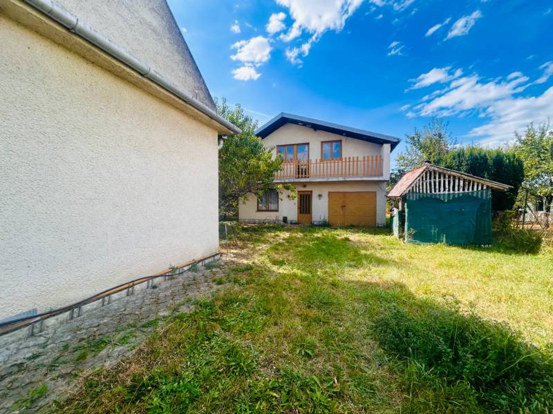 Rodinný dům v Sobrancích s prostornou zahradou, garáží a malým přístřeškem na pozemku.