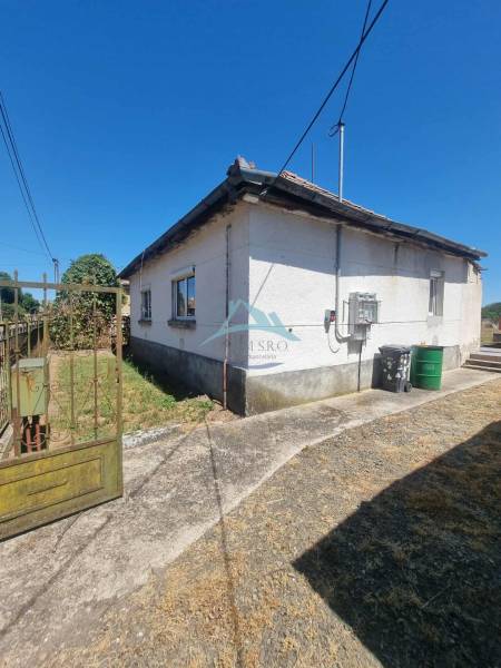 Rodinný dům v Ipolyveci se starou střechou, zamračený chodník a elektrické vedení.
