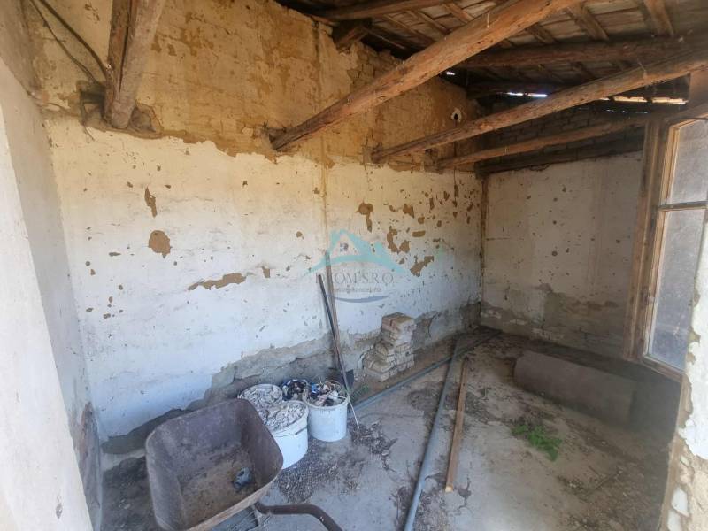 Interiér rodinného domu s poškozenými stěnami a starým stavebním vybavením.