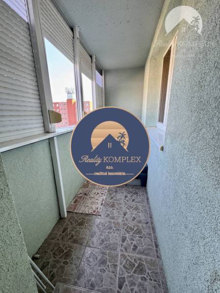 Balkon 4pokojového bytu s dlažbou a posuvnými okny na sídlišti.
