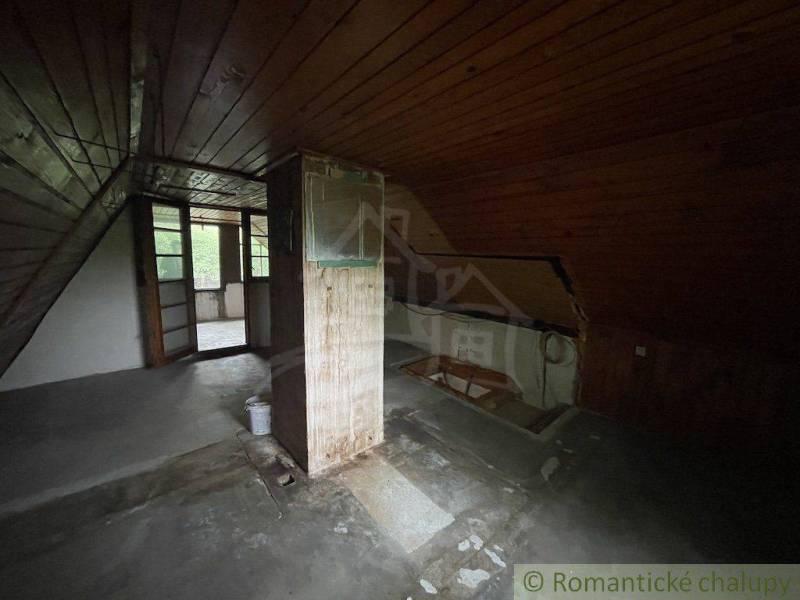 Podkrovní místnost s dřevěnými stěnami a podlahou v rodinném domě.