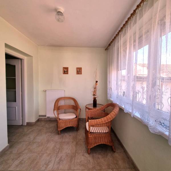 Prostorná místnost rodinného domu s proutěným nábytkem a elegantními záclonami.