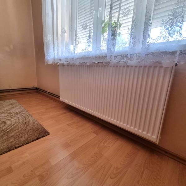 Pokoj s radiátorem pod oknem a závěsem v rodinném domě.