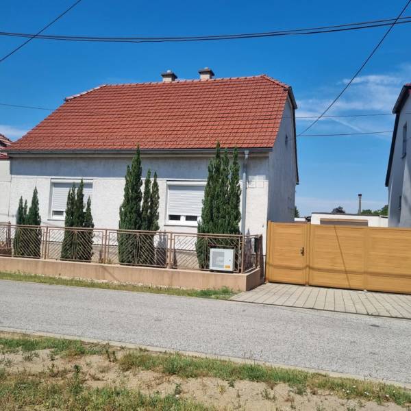 Rodinný dům na Riadku v Malackách s červenou střechou, předzahrádkou a dřevěnou bránou.