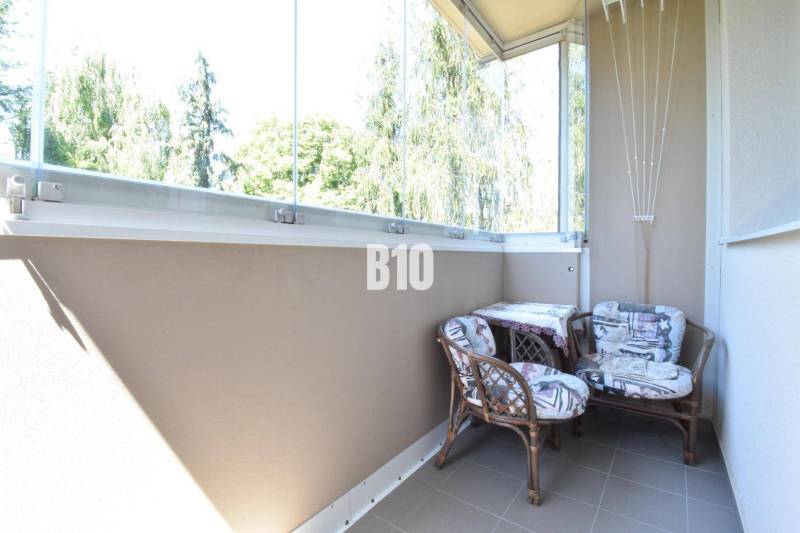 Zasklený balkon se dvěma židlemi ve 3pokojovém bytě s pěkným výhledem.