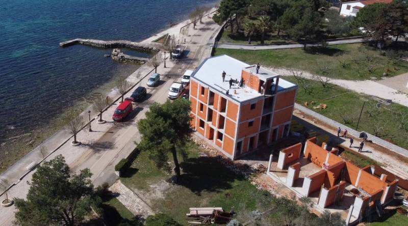 Stavební budova u moře ve městě Vir s přístupovou cestou a zelení.