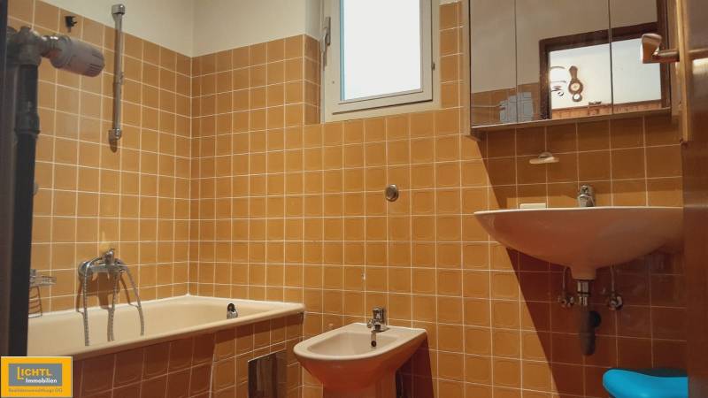 Koupelna s oranžovými kachličkami v rodinném domě, obsahuje vanu, bidet a umyvadlo.