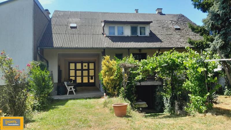 Rodinný dům v Potzneusiedlu se zahradou, rostlinami a viditelným patrem s okny.