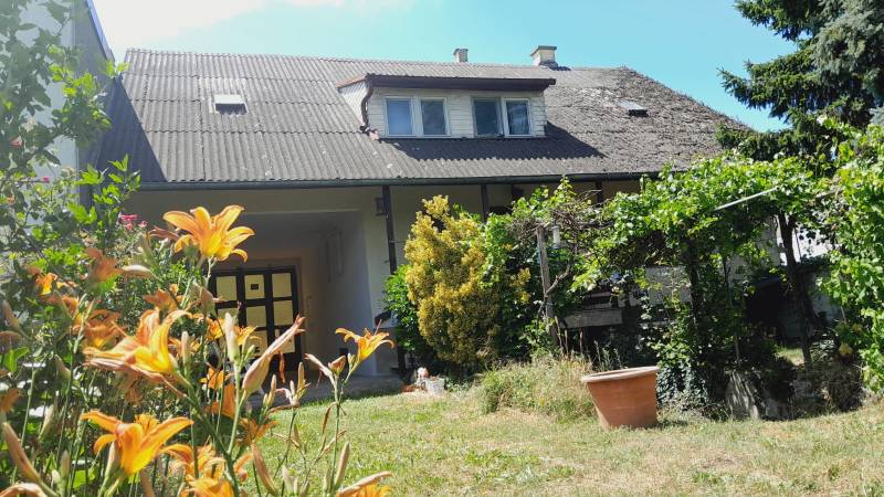 Rodinný dům v Potzneusiedlu s květinovou zahradou, vinicí a tradičním šikmým střešním designem.