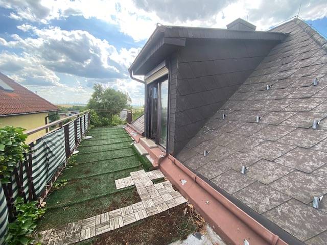 Podkrovní terasa rodinného domu v Hundsheime s výhledem a s trávníkovou plochou.