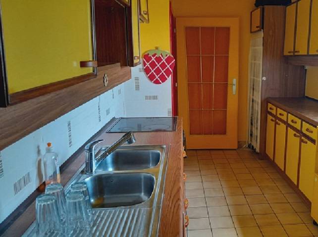 Kuchyně v rodinném domě se žlutými skříňkami a nerezovým dřezem.