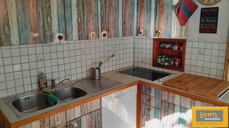 Kuchyně v rodinném domě s barevnými skříňkami a bílým obkladem.