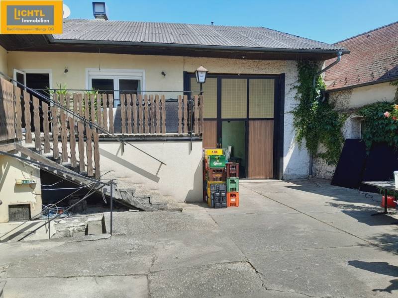Dvůr se schodištěm v gastro prostorech v Grossinzersdorfu, obklopený zelení a pivními přepravkami.