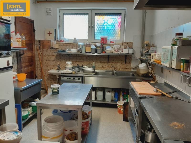 Kuchyně v gastro prostorech se stoly, nádobami a zařízením na vaření.