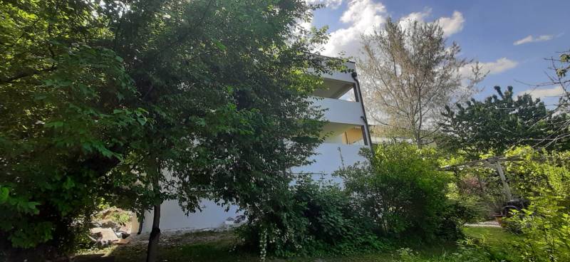 Vila v Hainburgu an der Donau obklopená zelení s částečně odkrytými poschodími.