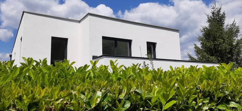 Vila v Hainburgu an der Donau s bílou fasádou, obklopená zelení pod modrou oblohou.