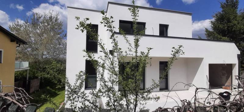 Vila v Hainburgu an der Donau s minimalistickou fasádou a okolím plným zeleně.