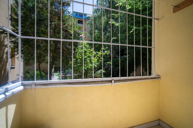 Malý balkon s výhledem na zeleň a dřevěné prvky v 3-pokojovém bytě.