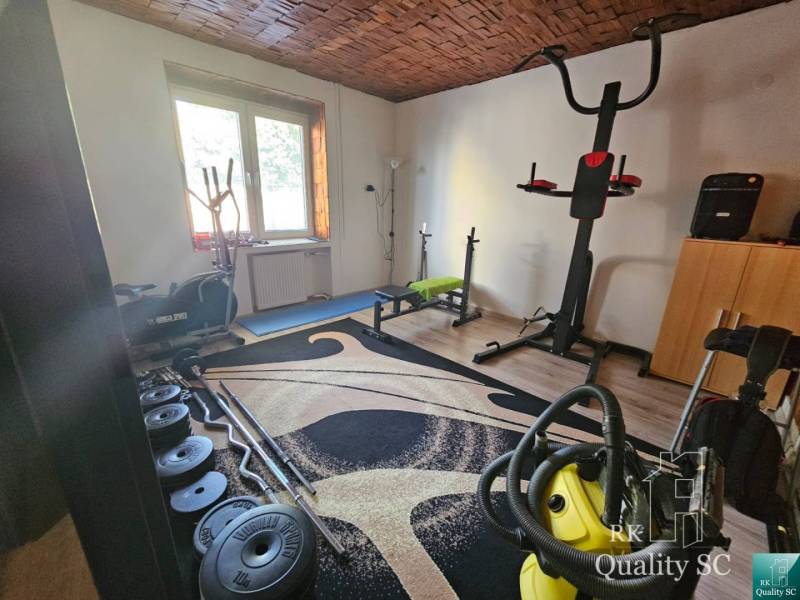 Domácí posilovna v rodinném domě se sportovním vybavením a činkami.