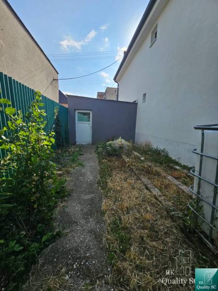 Rodinný dům na Rybničné ulici ve Velké Mači, úzký dvůr se zelení a betonovým chodníkem.