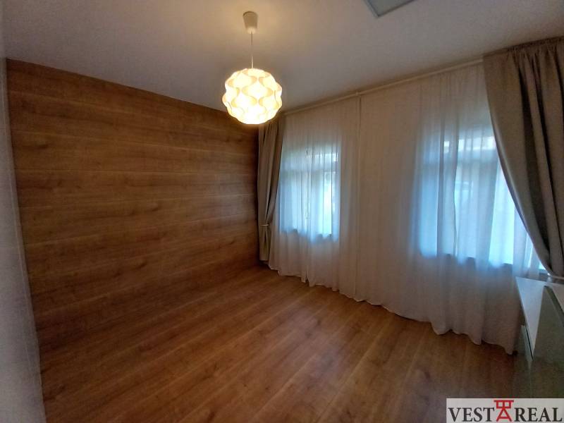 Pokoj v rodinném domě s dřevěnými obklady, podlahou a světlem na stropě.