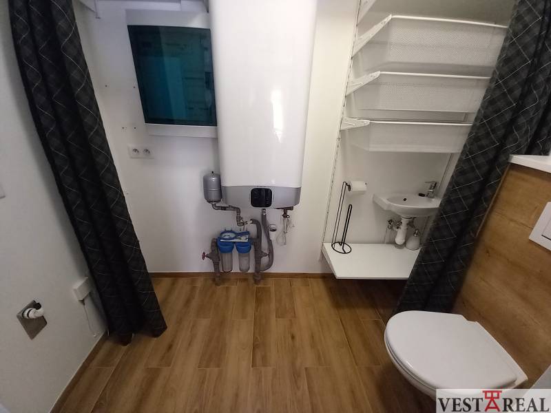 Koupelna v rodinném domě s kotlem, umyvadlem, toaletou a praktickým úložným řešením.