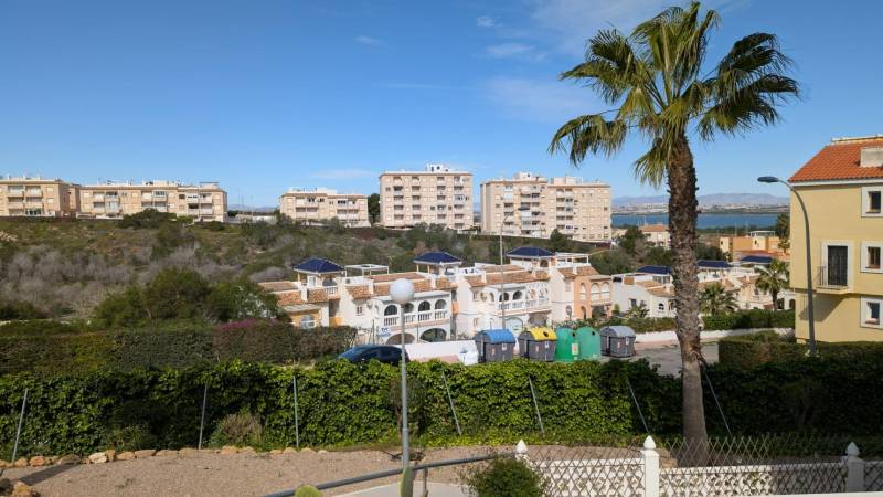 Pohled na obytné domy, stromy a kontejnery na ulici cl. Aquiles v Torrevieji.