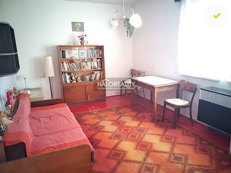 Obývací pokoj v rodinném domě se sedací soupravou a knihovnou.