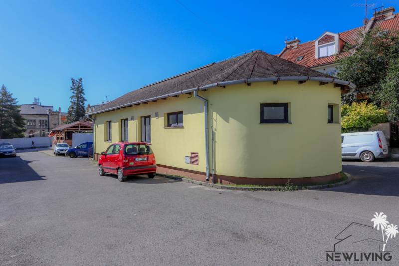 Žlutá budova na ulici Slovenského národního povstání ve městě Vrbové s parkujícím červeným autem.