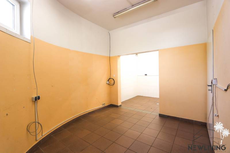 Interiér obchodních prostor s oranžovými stěnami a hnědou podlahou.