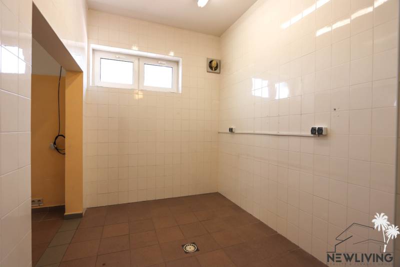 Kachličkovaná místnost se dvěma okny a ventilátorem v obchodních prostorách.