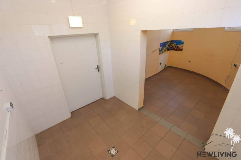 Kachličkovaná místnost s otvorem do vedlejší části, obchodní prostory s dlažbou.