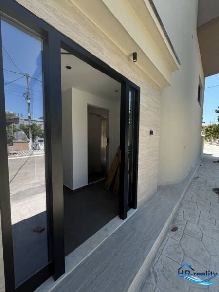 Vstup do Rekreačního apartmánu v Ksamil má prosklené dveře a světlý interiér.