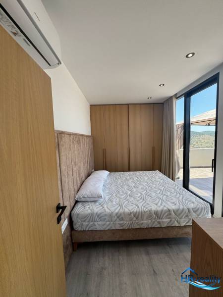Ložnice v rekreačním apartmánu s pohodlnou postelí, vkusným zařízením a balkonem.