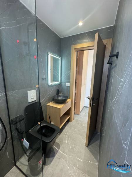 Koupelna v rekreačním apartmánu s černým sanitárním zařízením a dřevěným nábytkem.