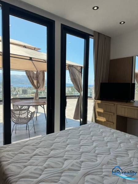 Interiér rekreačního apartmánu s postelí, skříní a terasou s výhledem na moře.