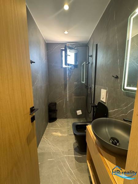 Koupelna v rekreačním apartmánu se sprchou, moderním umyvadlem a tmavou toaletou pro pohodlí.
