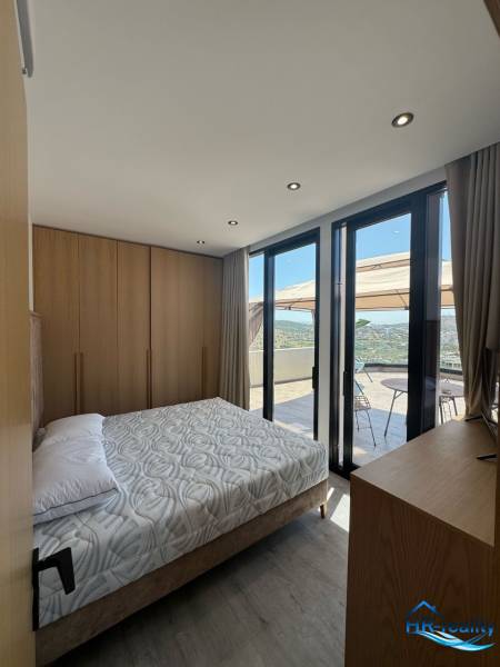 Ložnice v rekreačním apartmánu s výhledem z balkonu, dřevěný nábytek a postel.