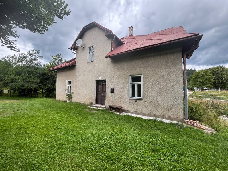 Rodinný dům v Makově na ulici Centrum, se zahradou a stromy v pozadí.