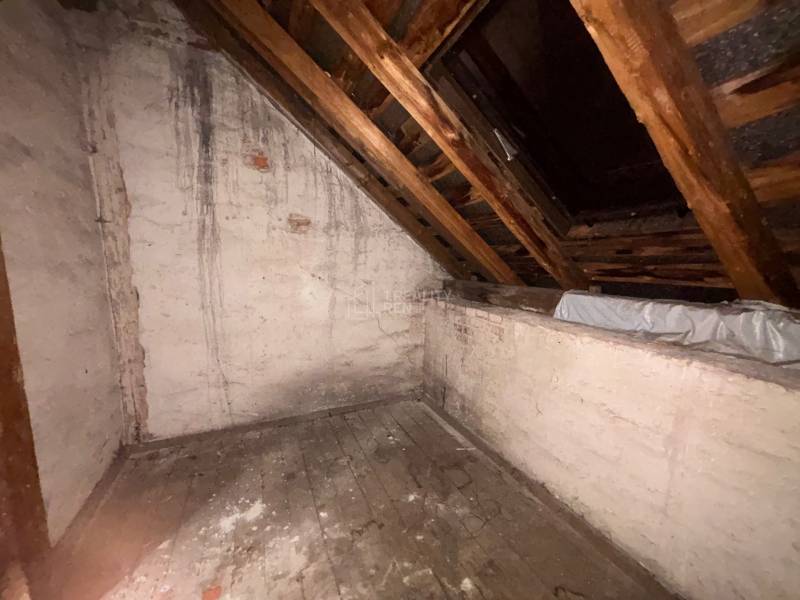 Půda v rodinném domě se starou dřevěnou podlahou a šikmým stropem.